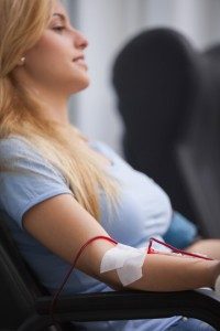 Smiling woman getting a transfusion and sitting on a chair in hospital