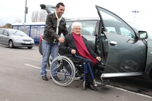 Nursing staff helping senior into vehicle.